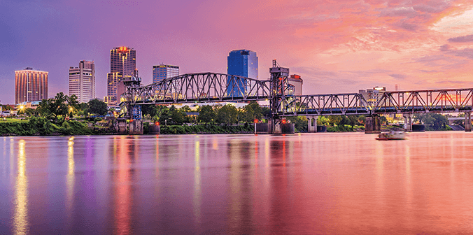 Little Rock, AR city skyline at sunset on the river with city and bridge